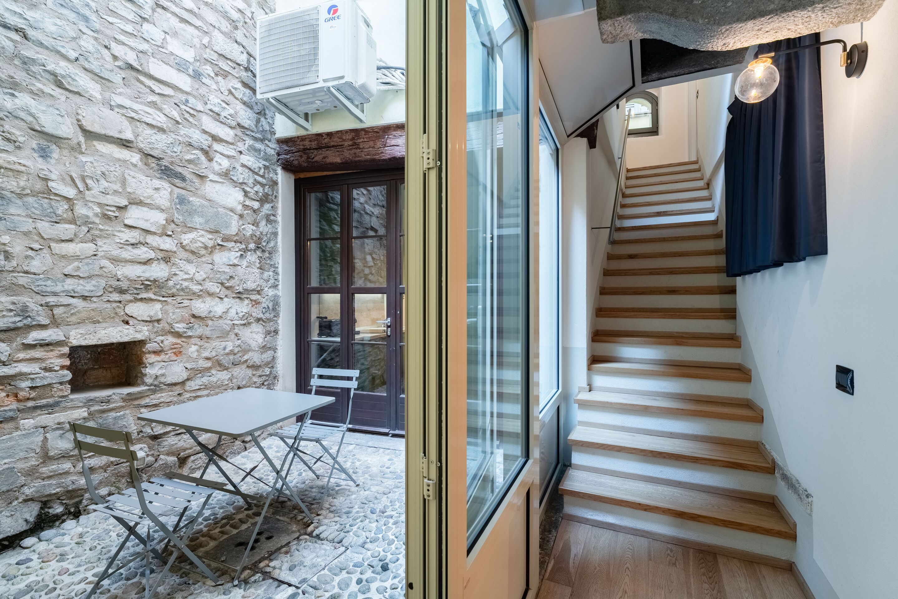 A stone wall, a table with chairs, and a staircase with wooden steps.