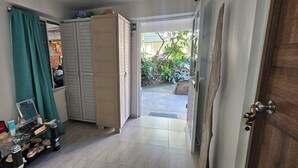 A hallway with a green curtain, a wooden door, and a view of a garden outside. - Posada Cedar Valley  (Providencia)