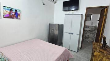 A bedroom with a bed, wardrobe, TV, and a small bathroom.