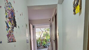 A hallway with a marble floor, a decorative wall with a floral pattern, and a door with a sign. - Posada Cedar Valley  (Providencia)