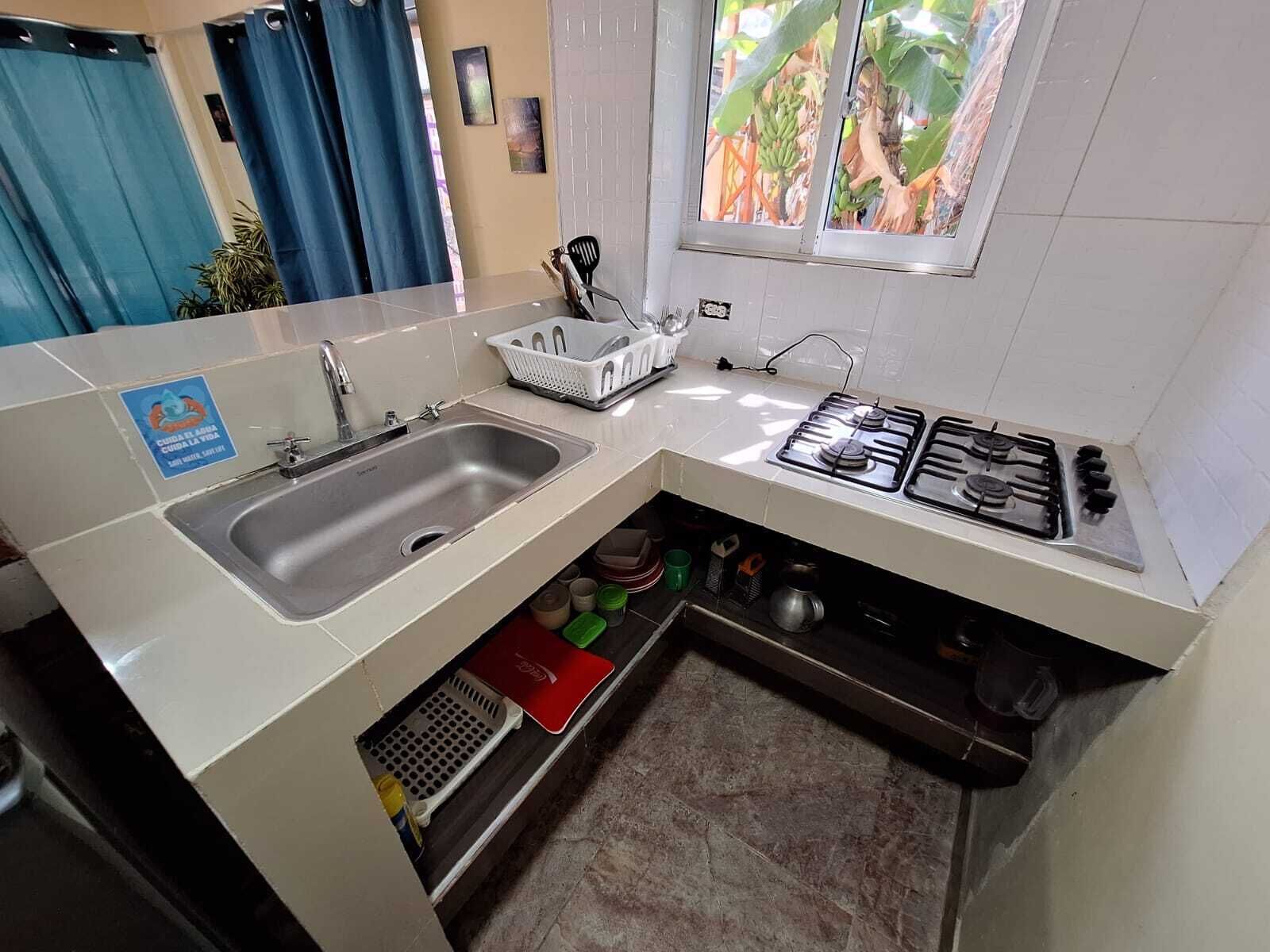A compact kitchen with a sink, stove, and storage shelves.