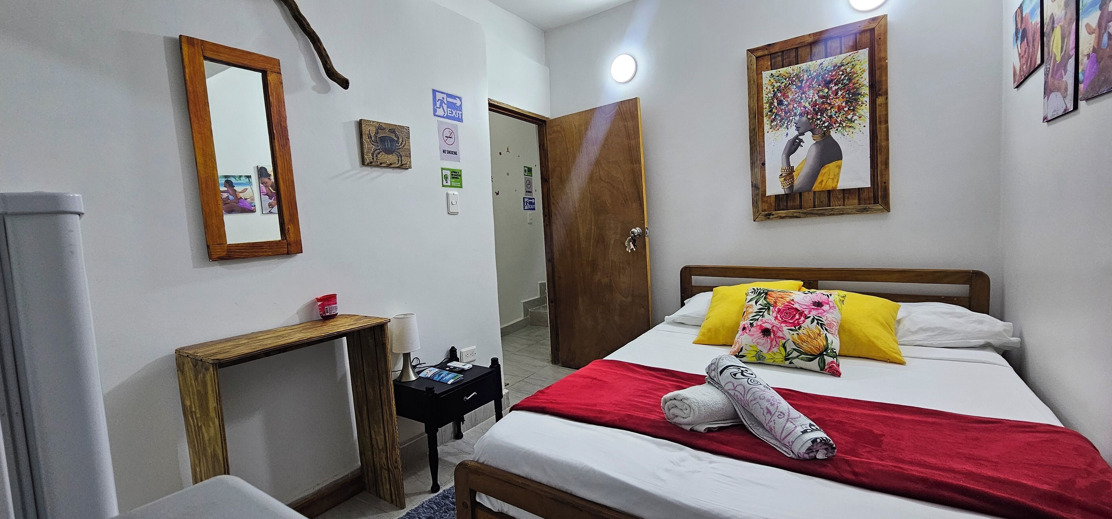 Una habitación de hotel con una cama, una mesita de noche, un espejo y una puerta.