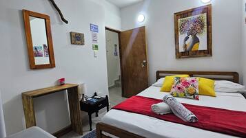 Una habitación de hotel con una cama, una mesita de noche, un espejo y una puerta.