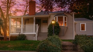Une maison à deux étages avec un porche, une cheminée et un lampadaire allumé.