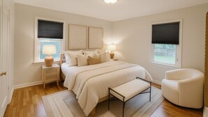 Une chambre à coucher avec un lit, des tables de chevet, une chaise et une fenêtre avec des stores.
