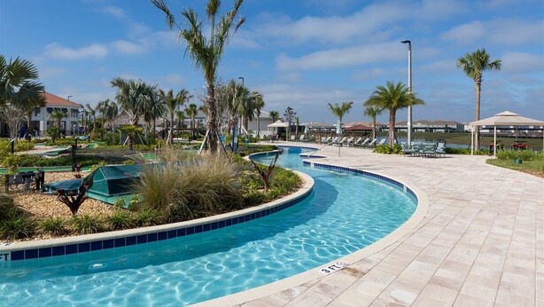 A pool area with a curved design, surrounded by palm trees and lounge chairs. - 4br/3ba Private Pool Storey Lake Resort Best Location Near Disney! (Kissimmee)