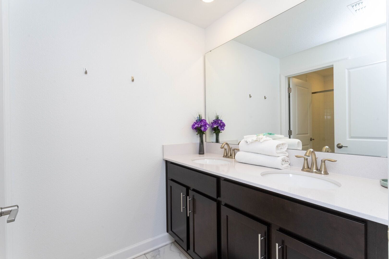 A bathroom with a white sink, dark cabinets, and a large mirror.