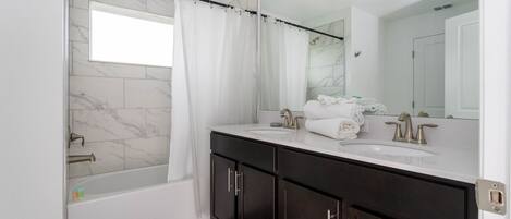 A modern bathroom with a bathtub, a large mirror, and dark wooden cabinets.
