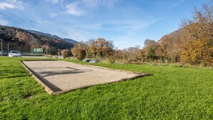 A grassy area with a paved section, trees, and a mountain in the background.