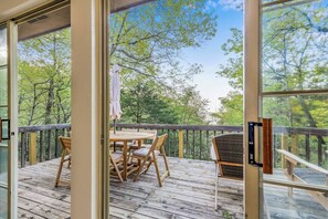 Une terrasse en bois avec une table et des chaises, donnant sur une zone boisée.