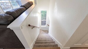 Een trap met een comfortabele bank aan de bovenkant, een klein raam en uitzicht op de omgeving.