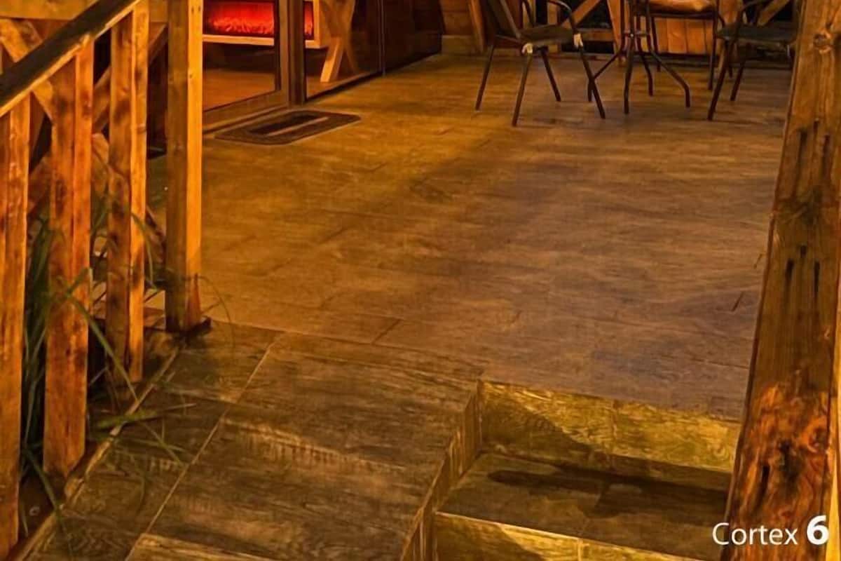 Un bâtiment moderne en bois, doté d’un toit triangulaire, de grandes fenêtres en verre et d’une terrasse en bois avec des chaises.
