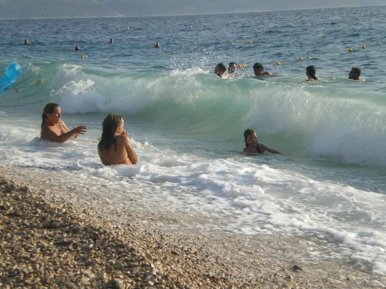 Ein Strand mit Menschen, die im Wasser schwimmen und spielen.