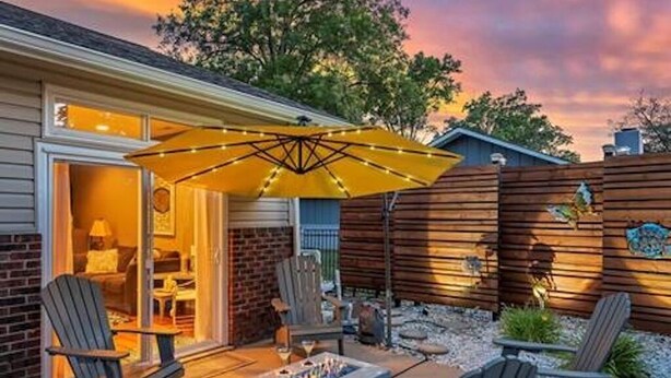 An outdoor patio with Adirondack chairs, a fire pit, and a yellow umbrella. - St Louis Co- Tranquil 2-bed/1 bath house -STL County-Sleeps 1-4 (Ballwin)