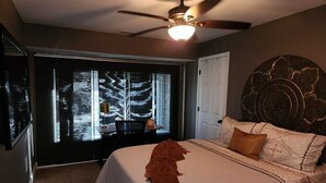 A bedroom with a bed, a ceiling fan, a window with a view of trees, and a door. - St Louis Co- Tranquil 2-bed/1 bath house -STL County-Sleeps 1-4 (Ballwin)