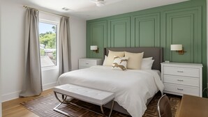 A bedroom with a large bed, bedside tables, a bench, and a view of greenery outside. - Create amazing stories in the treetops of Atlanta! (Atlanta)