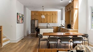 A modern kitchen with wooden cabinets, a central island, and a dining area with a sofa and chairs. - Create amazing stories in the treetops of Atlanta! (Atlanta)