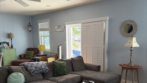 Una sala de estar con un sofá modular, un reposapiés y un ventilador de techo.