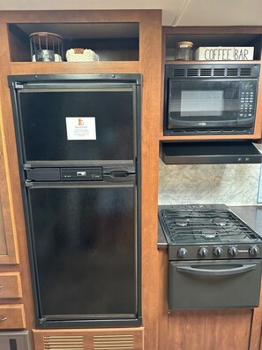 A kitchen with a black refrigerator, a microwave, and a gas stove.