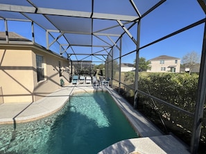 A covered swimming pool with clear water, surrounded by a metal frame and glass panels.