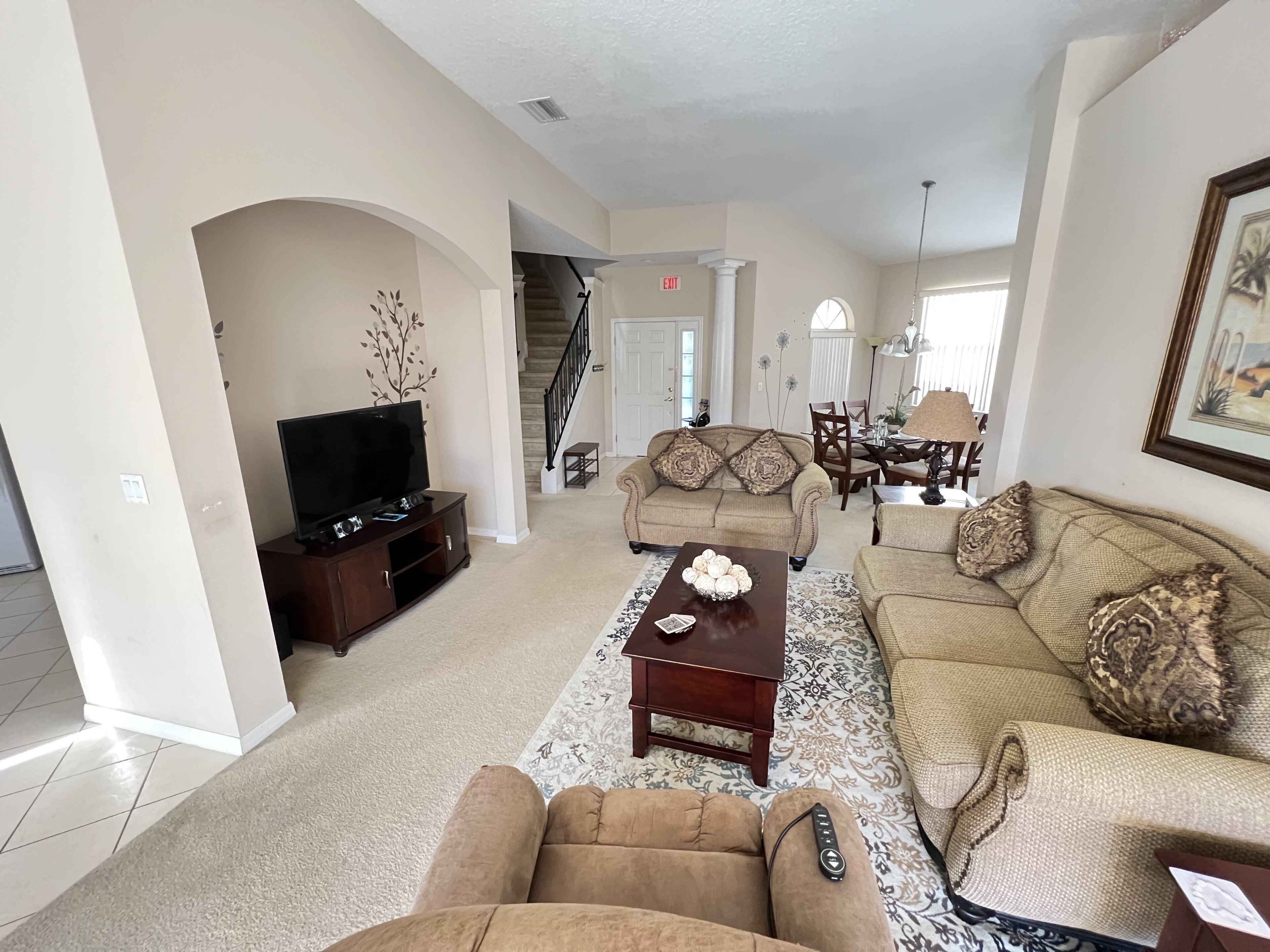 A spacious living room with a television, two sofas, a coffee table, and a staircase leading to another level.
