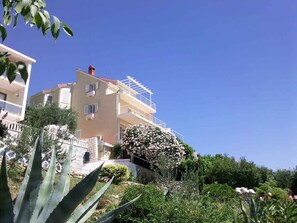 Un immeuble à plusieurs étages doté de balcons, entouré de verdure et de cactus.