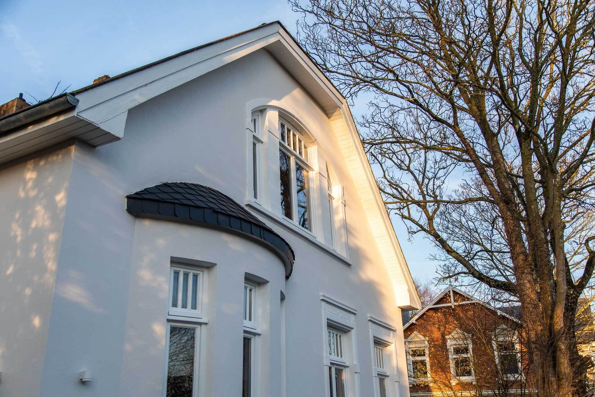 Een wit gebouw met een gebogen dak en meerdere ramen.