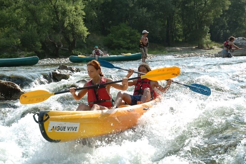 Un groupe de personnes pratiquant le kayak sur une rivière bordée d’arbres.