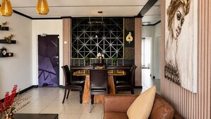 A modern living room with a dining area, featuring a sofa, chairs, a coffee table, and a decorative wall panel.