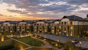 A modern apartment complex with multiple units, a playground, and solar panels.