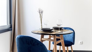 A dining area with a round table, two chairs, a vase with dried flowers, and two wine glasses. - Regras Apartments & Garden A1 by Benefit Collection (Porto)