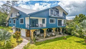 A two-story house with a balcony, a covered patio, and a well-maintained garden.