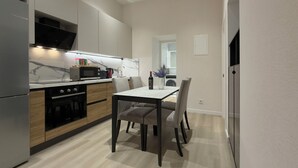 Een moderne keuken met een eethoek, voorzien van een inbouwoven, magnetron en een eettafel met stoelen.