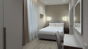 Een moderne hotelkamer met een bed, nachtkastje, stoel, grote spiegel en een schilderij aan de muur.