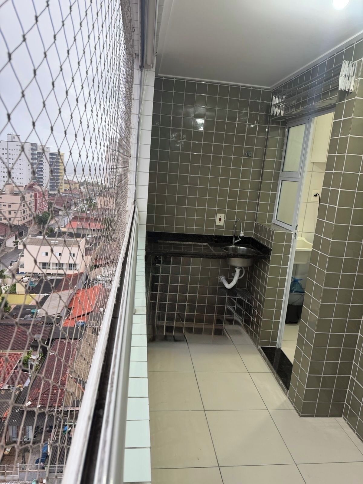 Un petit balcon donnant sur une vue de la ville, des murs carrelés et un évier.
