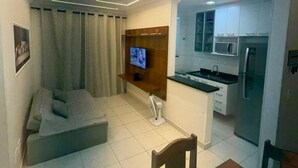 A compact living space with a kitchenette, a dining area, and a seating area with a TV. - Apartment in Praia Grande with parking, close to the sea (Praia Grande)