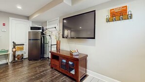 Eine moderne Küche mit Edelstahlgeräten, einem Holzschrank und einem an der Wand befestigten Flachbildfernseher.