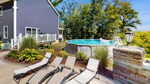Ein Wohnhaus mit Swimmingpool, Liegestühlen und einer Steinmauer.