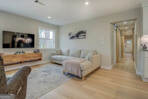 Una sala de estar moderna con sofá, televisor y mueble de madera.