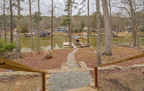 A residential area with a dock extending into a lake, surrounded by trees and houses.