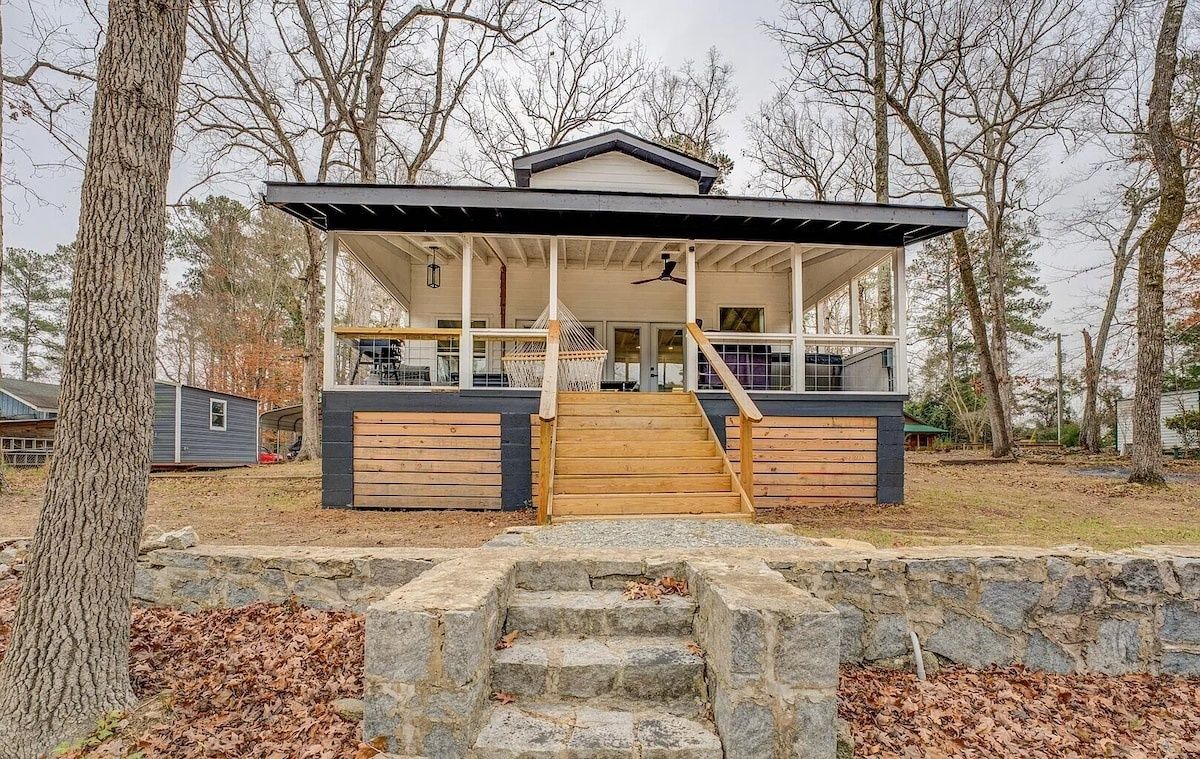 A modern house with a covered porch, stone steps, and a basketball hoop.