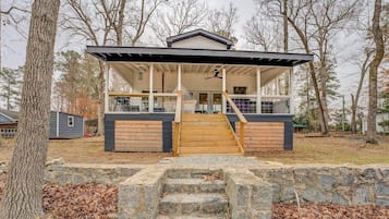 A modern house with a covered porch, stone steps, and a basketball hoop.