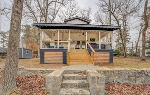 A modern house with a covered porch, stone steps, and a basketball hoop.
