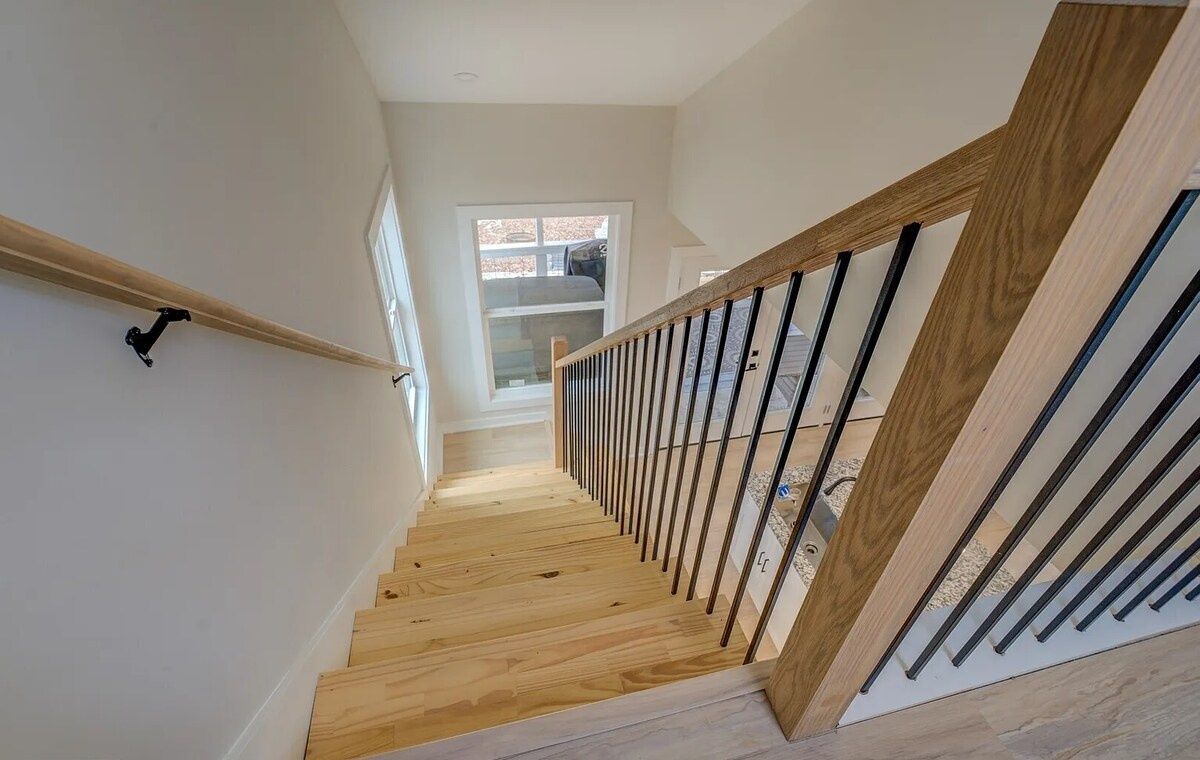 A wooden staircase with a glass railing, leading to a landing with a window.
