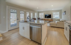 A spacious kitchen with a central island, a dishwasher, and a dining area with a sofa and TV.