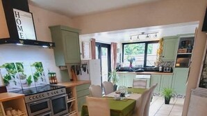 A spacious kitchen with a dining area, featuring a large stove, oven, and green cabinets. - Casa Douglas (Lifford)