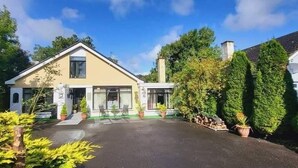 A two-story house with a covered patio area, surrounded by greenery and potted plants. - Casa Douglas (Lifford)