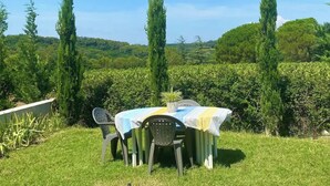 An outdoor dining area with a table and chairs, surrounded by greenery and trees. - Château Juliette 4* Provence wine estate (Tresques)