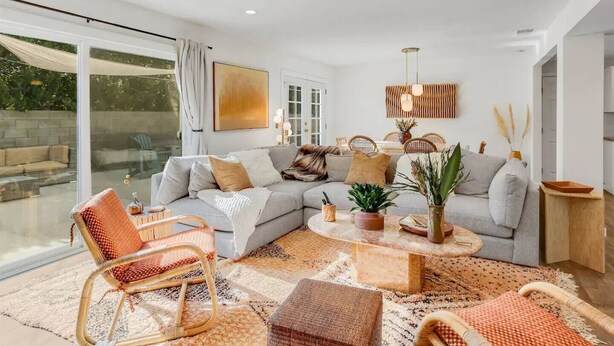 Una sala moderna con un sofá modular, una mesa de centro, sillas de mimbre y un ventanal con vistas al exterior.