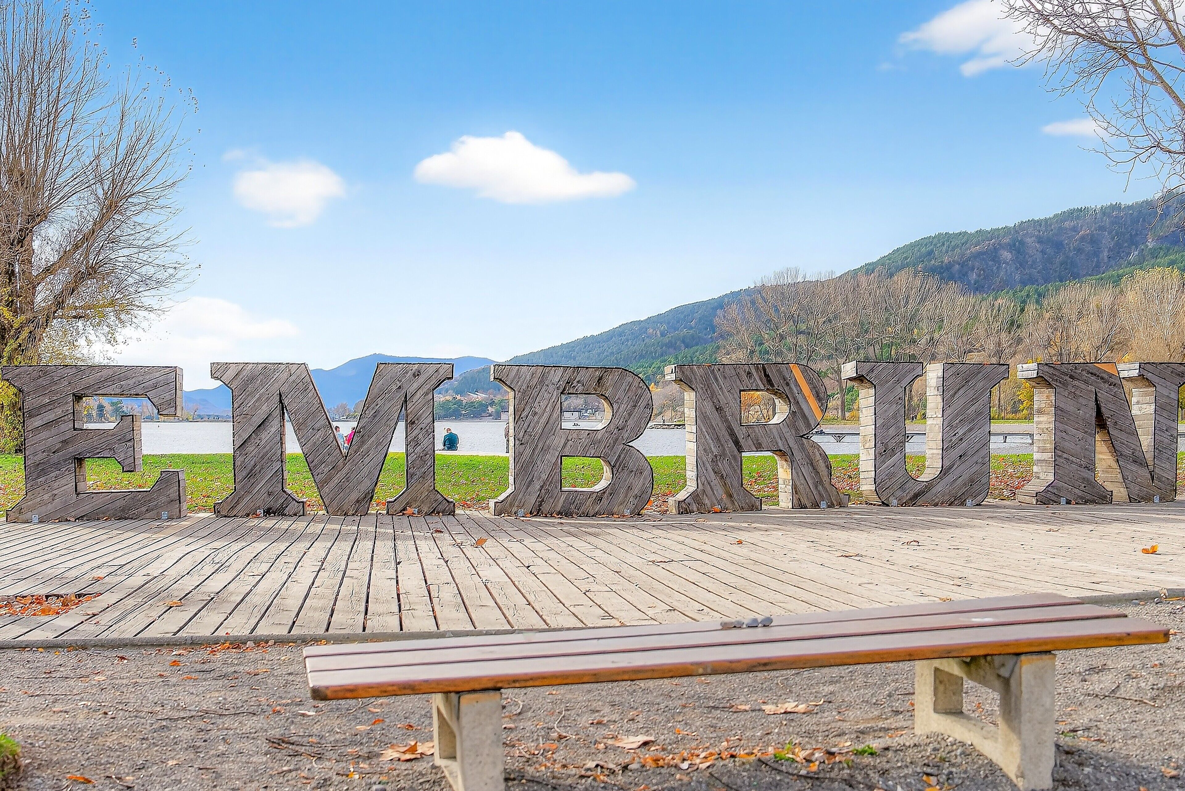 Una terraza de madera con un banco y un letrero grande de madera que dice 'EMBRUN'.
